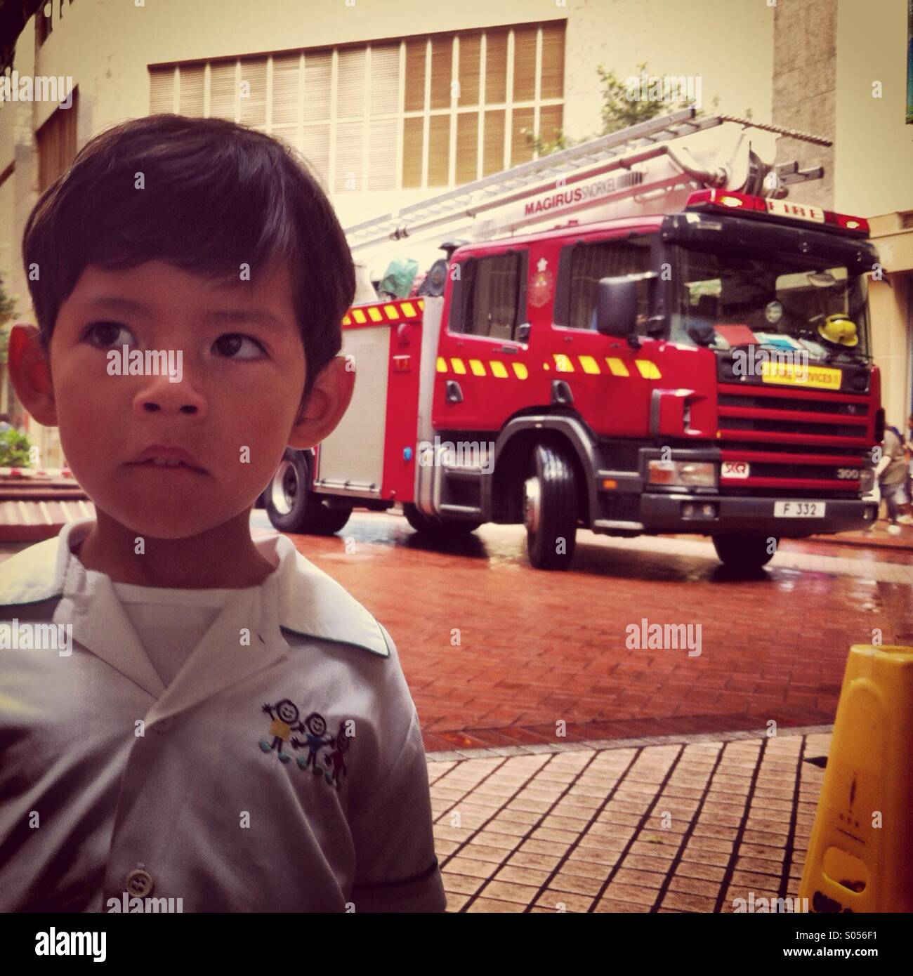 It's a photo of a child who is worry because of the firemen intervention with their firetruck Stock Photo
