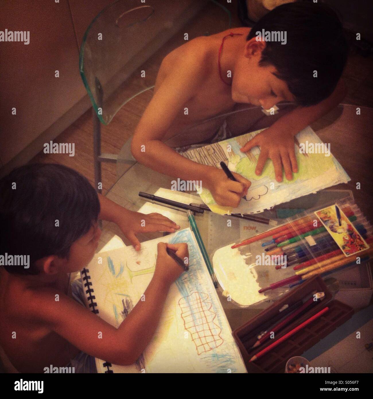 It's a photo of two kids doing homeworks.  They are two brothets drawing together - Smartphone Captured Stock Image