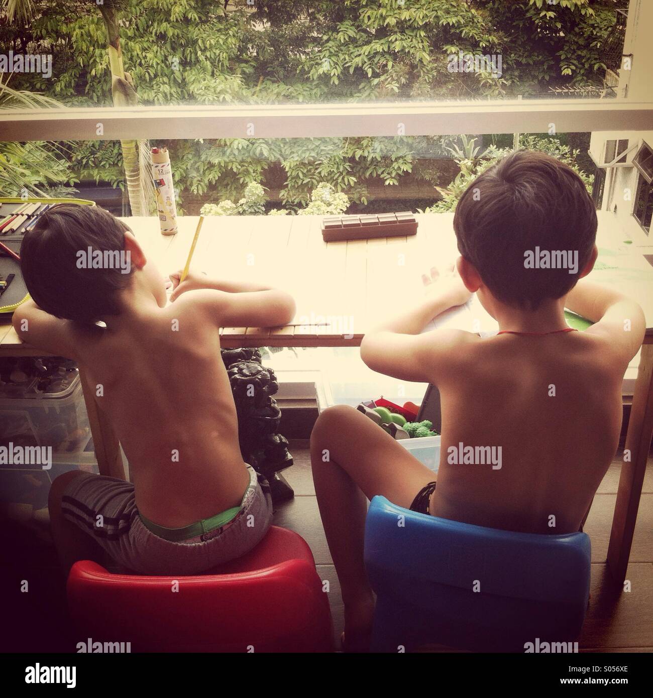 It's a photo of two brothers who are doing their homework facing the window. We see them from the back - Smartphone Captured Stock Image