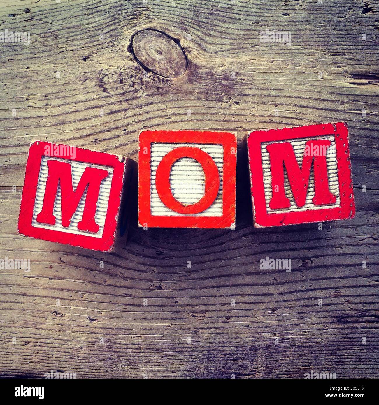 It's a photo of two wood cubes toy with letters that form the word MOM Stock Photo
