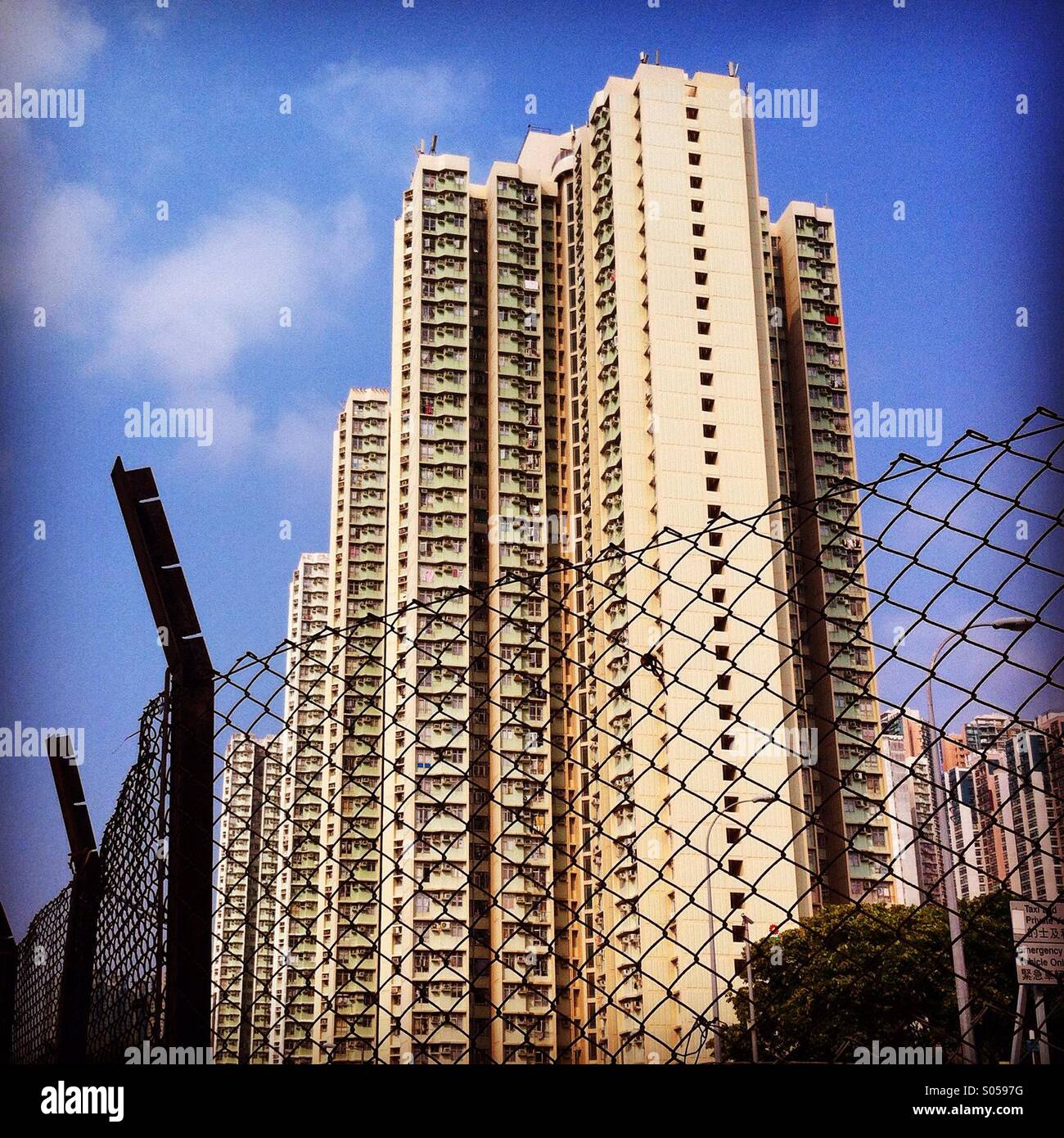 It's a photo of an habitation tower in hong kong. We see a wore fence in tje front Stock Photo