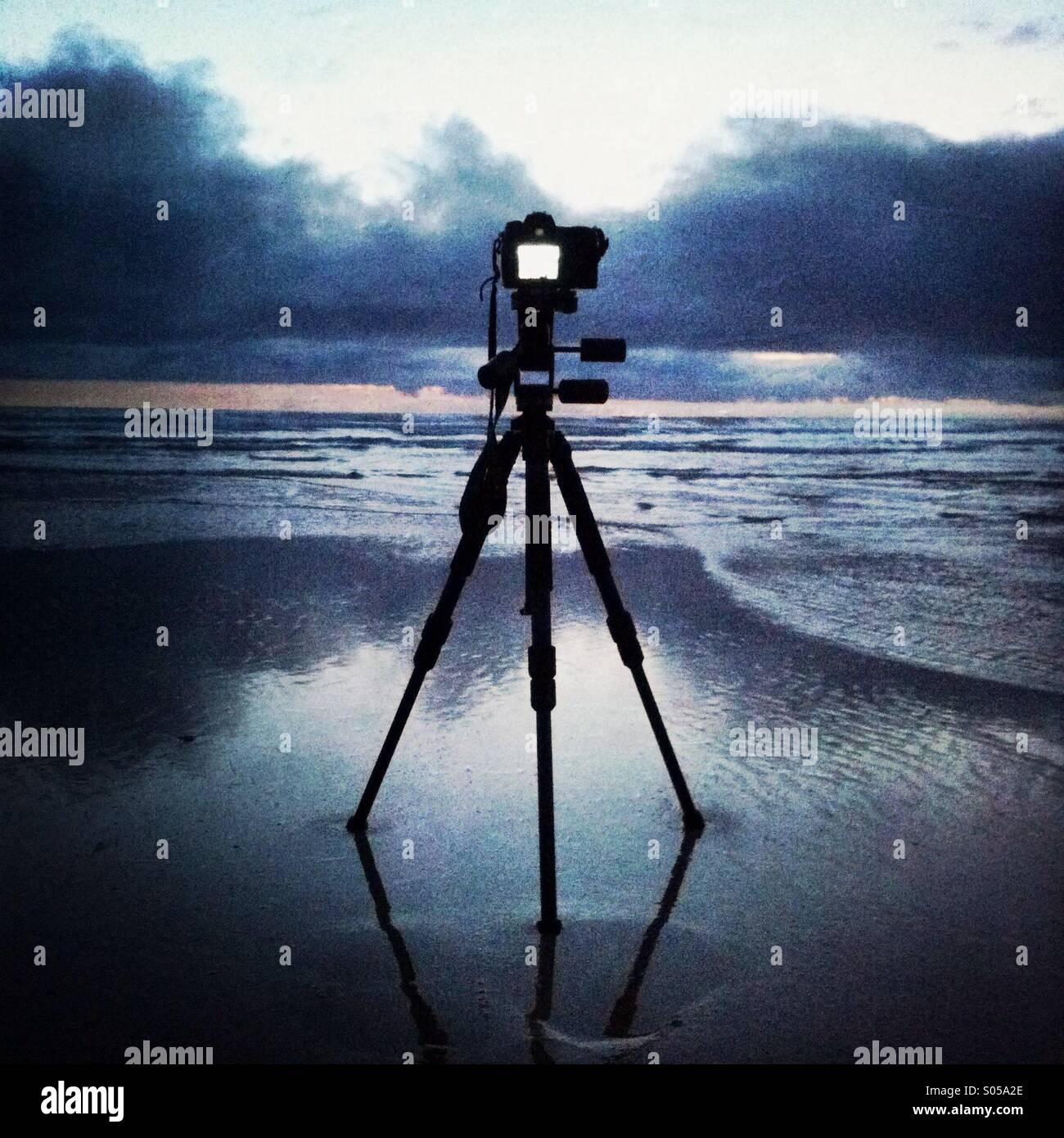 A camera on a tripod captures the sunset on the beach at Watergate Bay. Newquay, Cornwal, England UK. Stock Photo