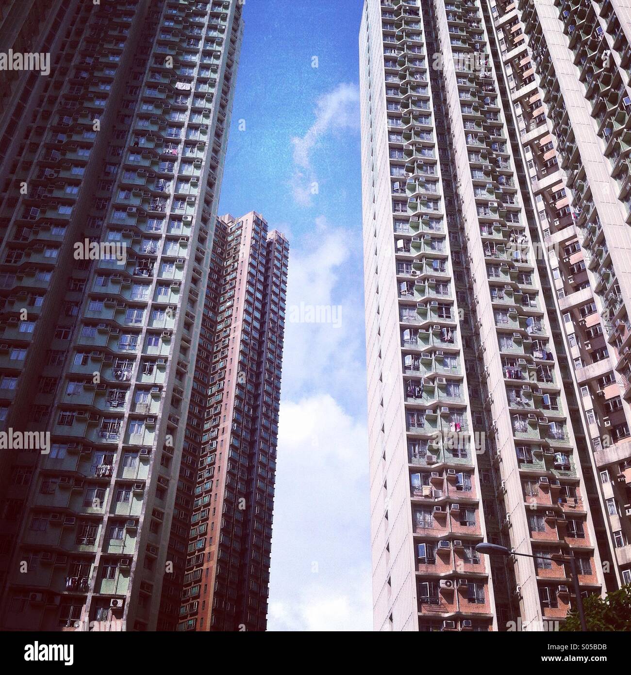 It's a photo of a narrow space between 2 high towers in Hong Kong. We can see a small area of blue sky - Smartphone Captured Stock Image