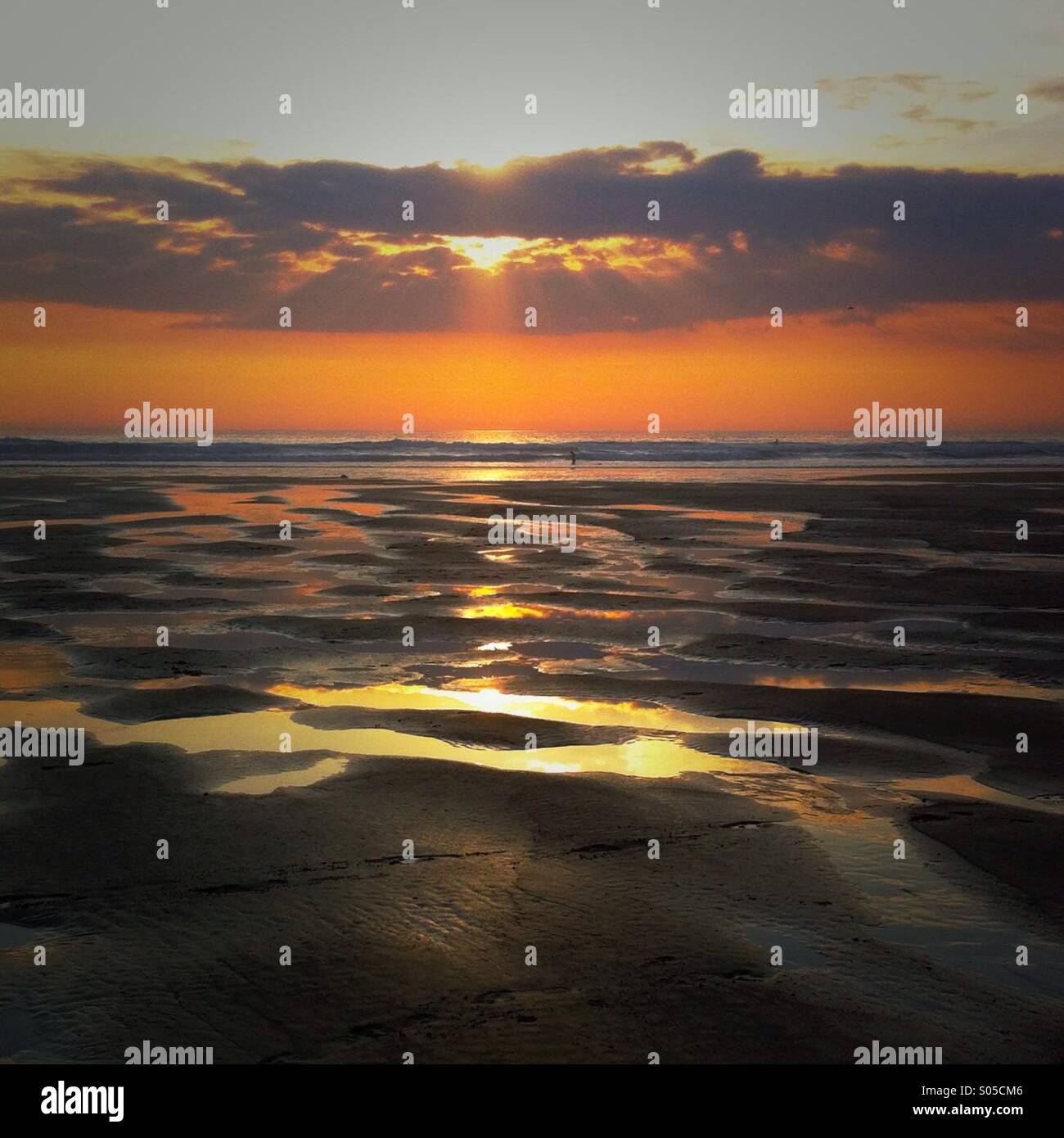 A sunset on the beach with pools of water reflecting the sunset. Watergate Bay, Newquay Cornwall England UK. - Smartphone Captured Stock Image
