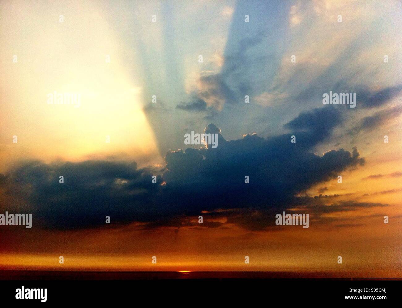 Rays coming through clouds from a sunset on the beach.  Watergate Bay, Newquay, Cornwall, England UK. - Smartphone Captured Stock Image