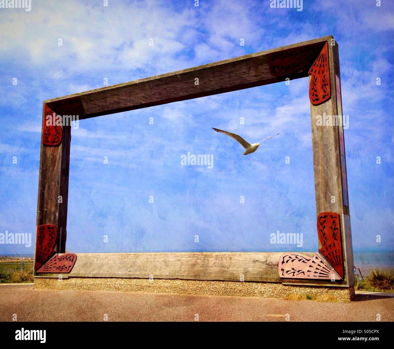 Seagull flying through picture frame sculpture on Morecambe promenade - Smartphone Captured Stock Image