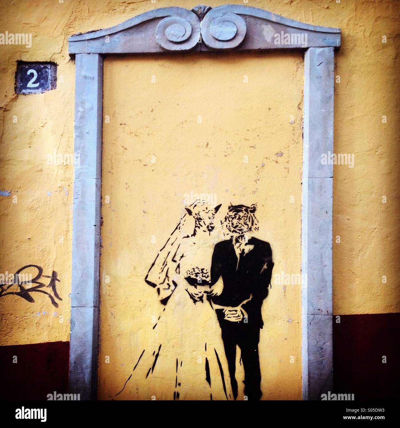 A graffiti displaying a weeding of a female wolf and a male tiger decorates a sealed yellow door in Guanajuato, Mexico - Smartphone Captured Stock Image