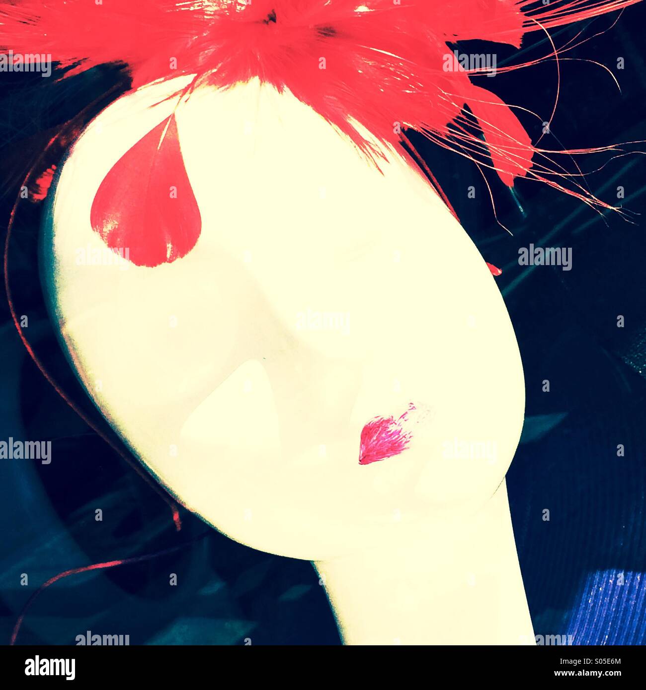 White female mannequin head with purple lips and red feather hat - Smartphone Captured Stock Image
