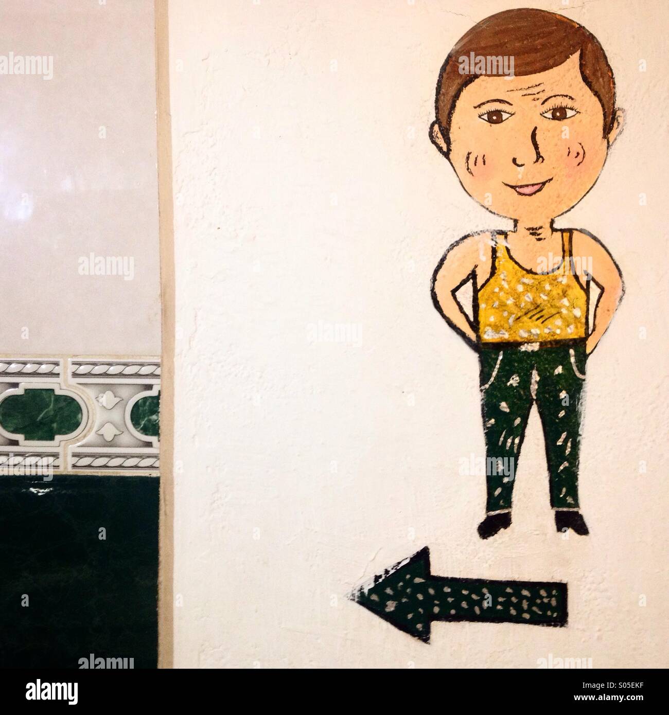 A painting of a man and a green arrow decorates publics bathrooms in Guanajuato, Mexico - Smartphone Captured Stock Image