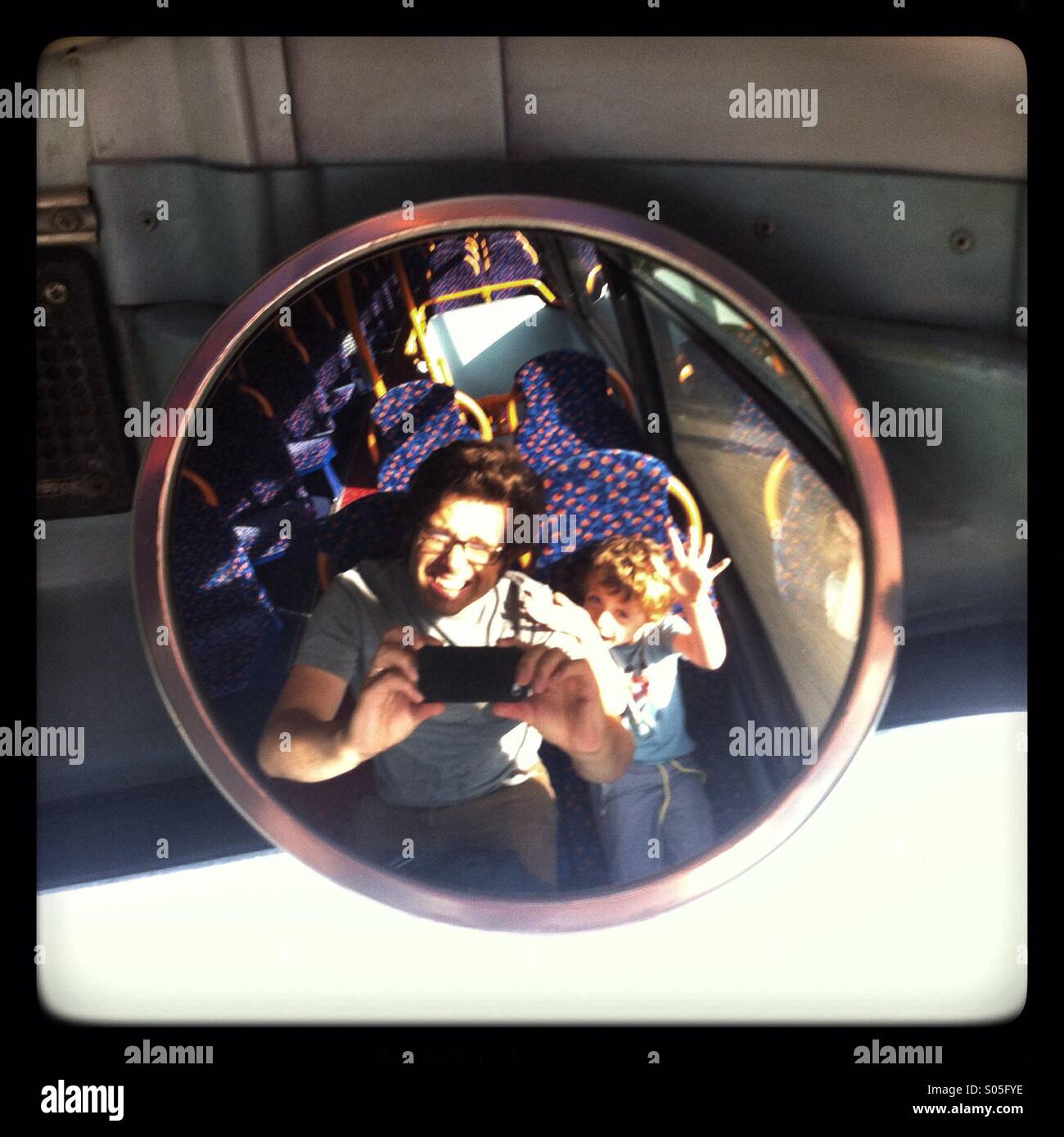 Father and son having fun on the top deck of a bus - Smartphone Captured Stock Image