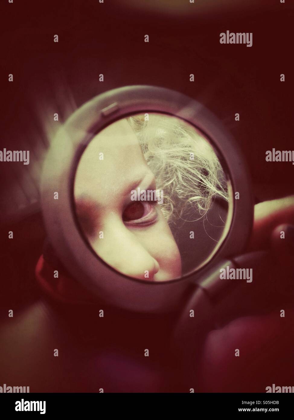 Young girl looking at herself in hand mirror Stock Photo