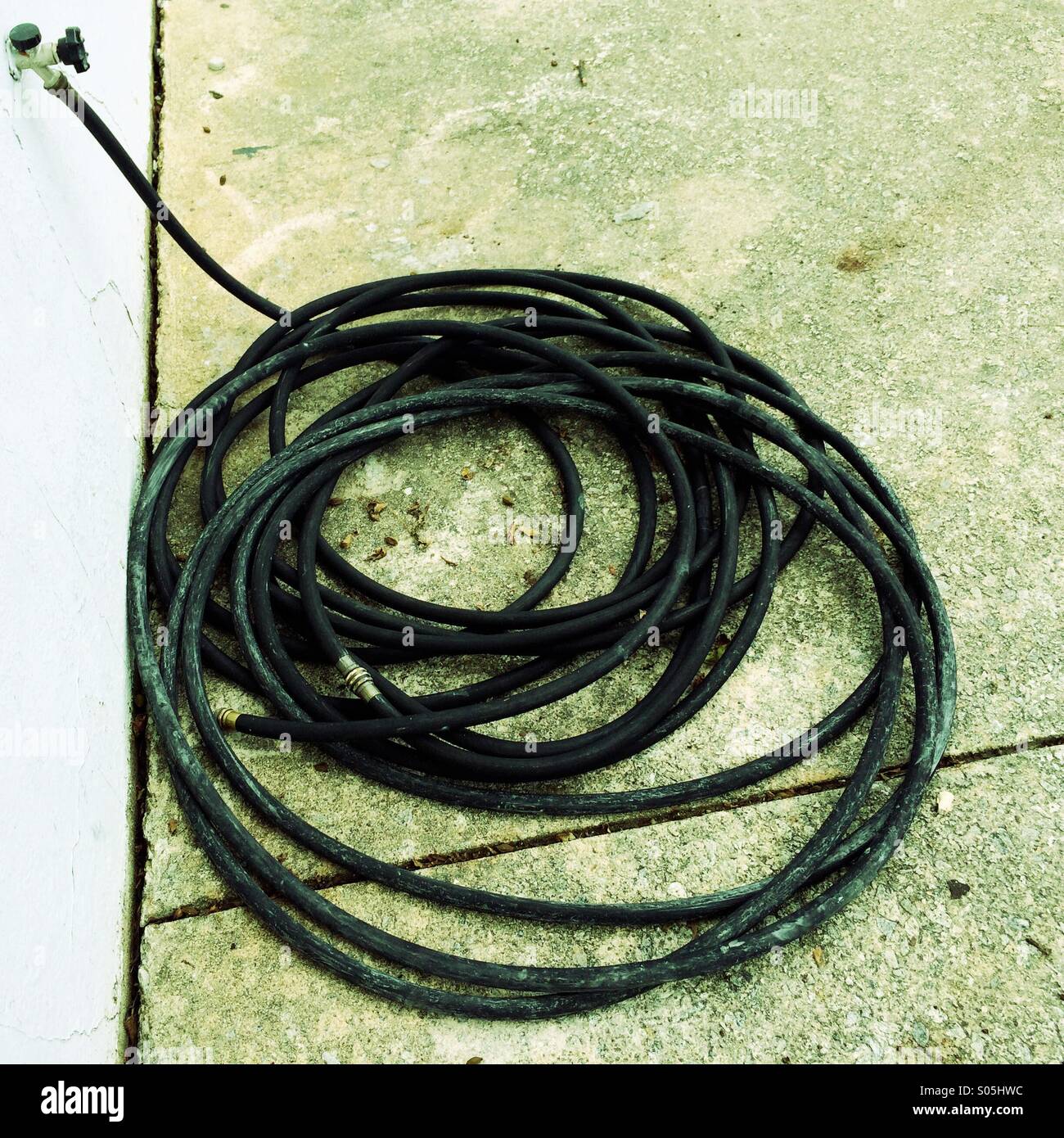 Rolled up hose on a sidewalk. - Smartphone Captured Stock Image