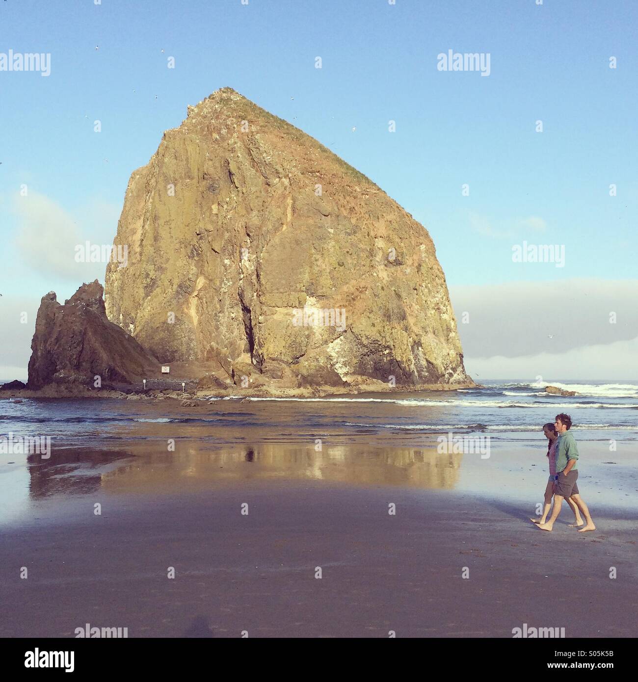 Couple walking, Haystack Rock, Cannon Beach, Oregon coast, - Smartphone Captured Stock Image