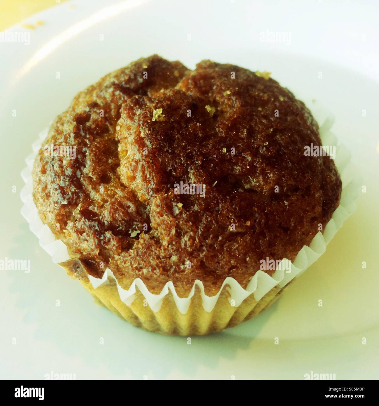 A healthy raisin bran muffin on a white plate. - Smartphone Captured Stock Image