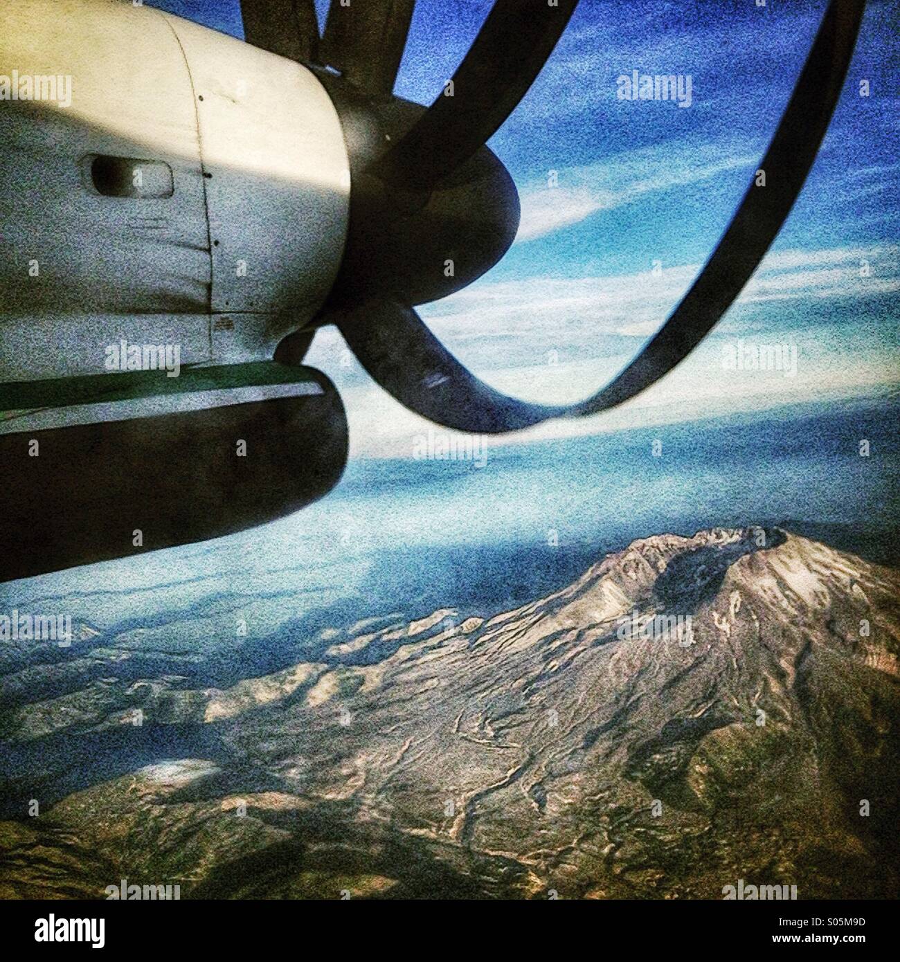 Turbo Prop airplane flying over Mt ST Helens with Mt Hood in the distance. Stock Photo