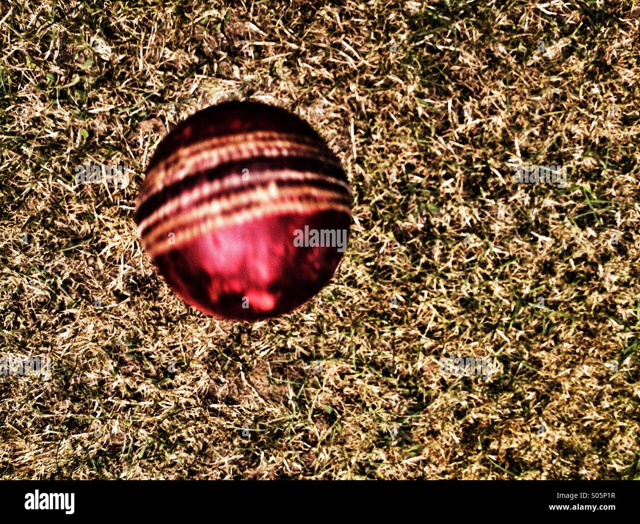 Overhead shot of spinning cricket ball in flight above the grass Stock