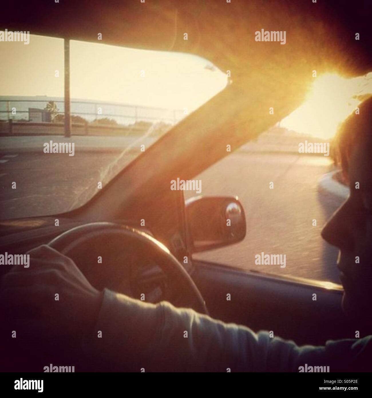 Female driving a car with flared sunlight coming through the window - Smartphone Captured Stock Image