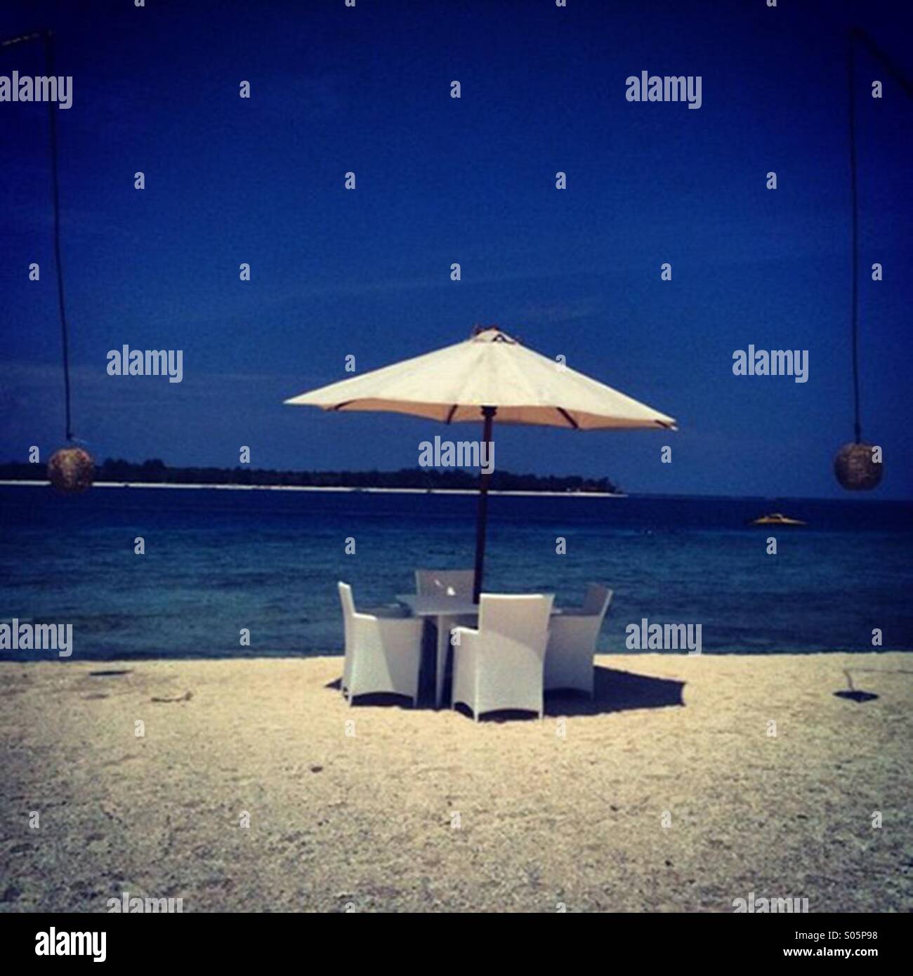 Resort table and chairs on the beach of Gili Meno, Indonesia - Smartphone Captured Stock Image