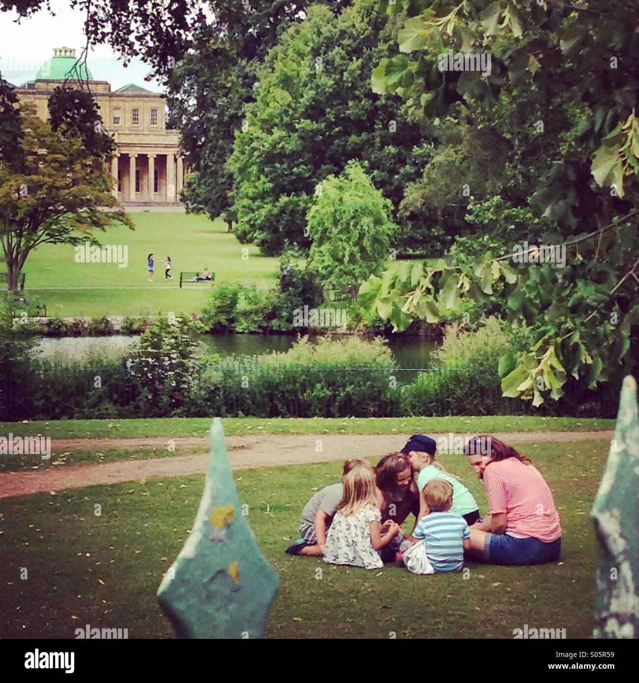 Games with family and friends on the grass in Pittville Park, Cheltenham in the summer, with Pittville Pump Rooms in the background Stock Photo