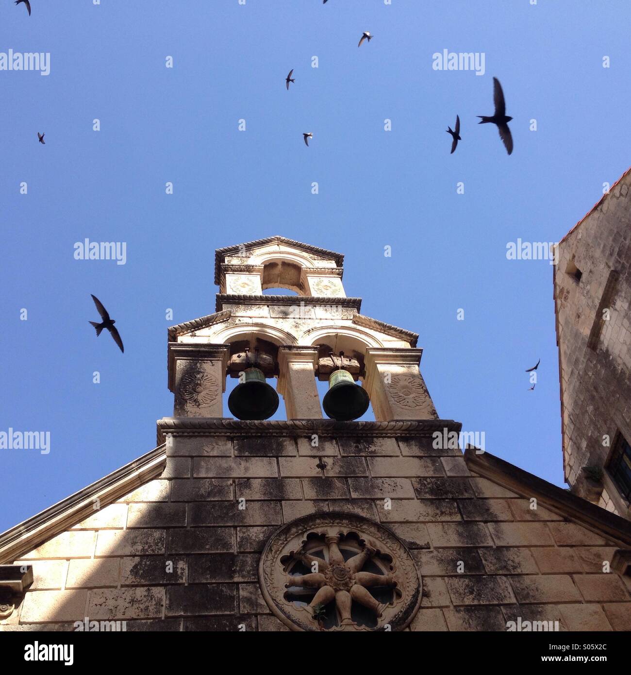 Birds flying by a chapel with church bells - Smartphone Captured Stock Image Birds flying by a chapel with church bells - Smartphone Captured Stock Image