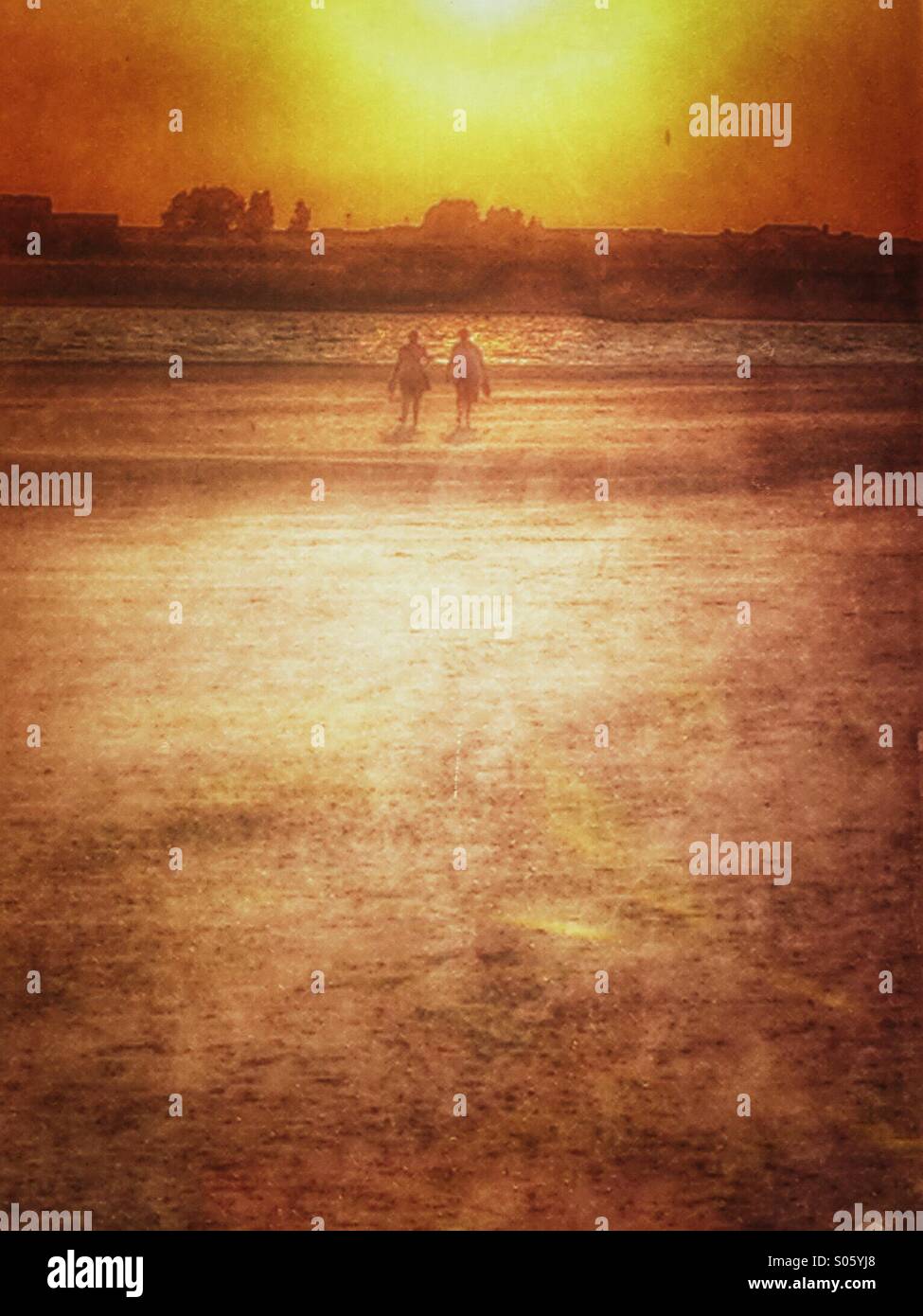 Two people walking on the beach at sunset - Smartphone Captured Stock Image