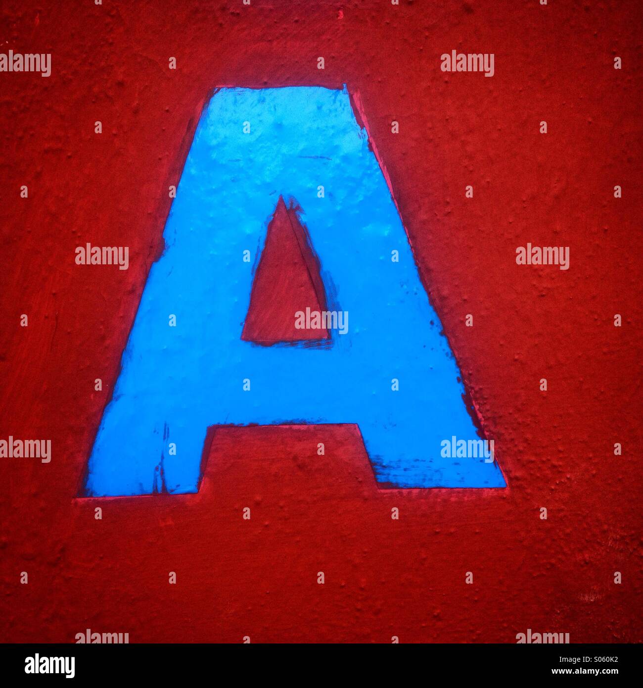 A blue letter A decorates a red wall in Merida, Yucatan, Mexico - Smartphone Captured Stock Image