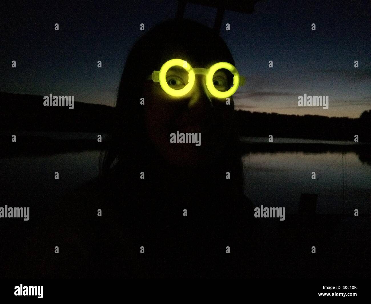 Silhouetted view of a woman wearing a pair of glow stick glasses at