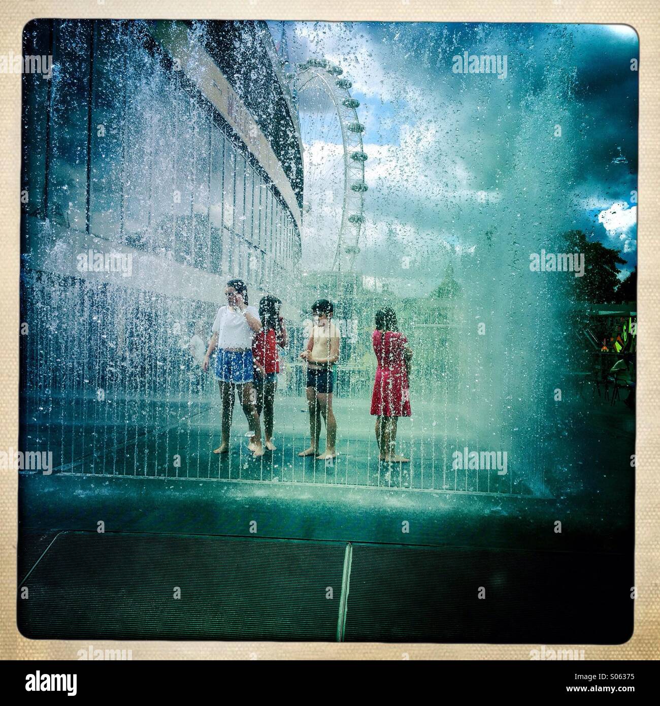 Children standing in the water jets, fountain out side Festival Hall on the South Bank on a sunny summers day. Stock Photo