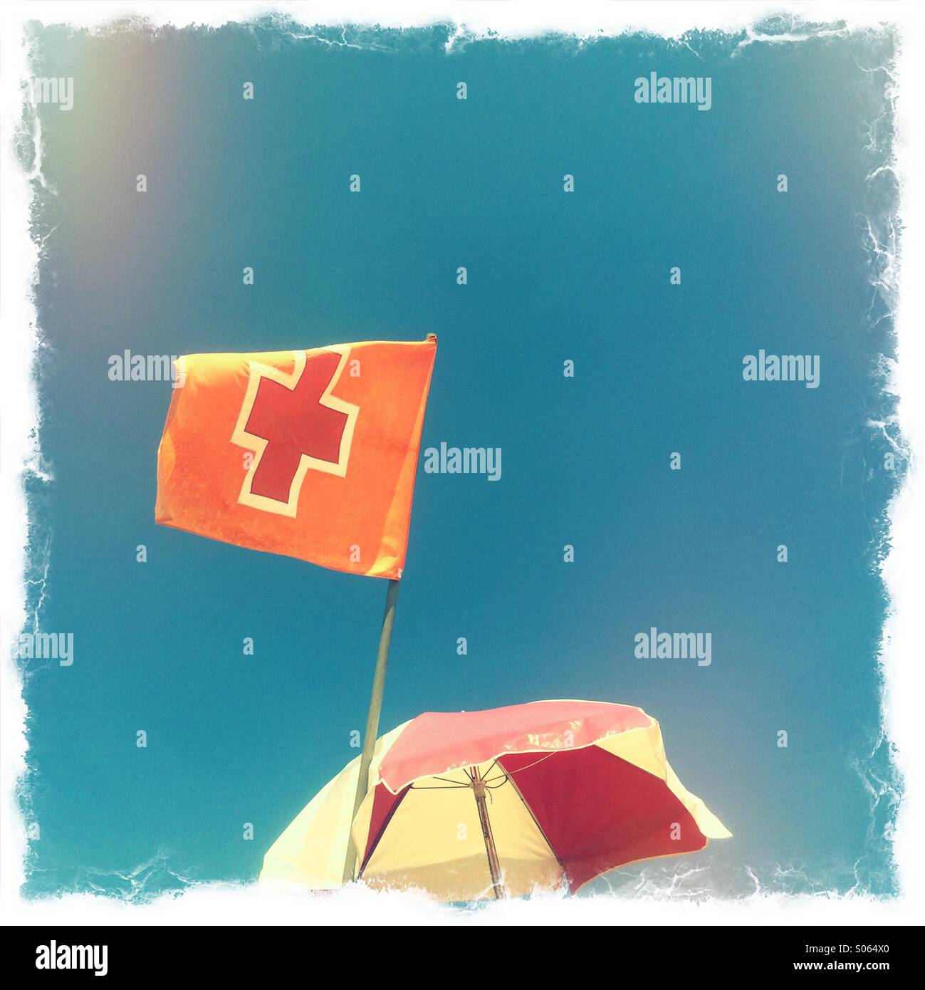 A Red Cross flag and an umbrella for shade over a lifeguard's chair at the beach, Jacksonville Beach, Florida, USA. - Smartphone Captured Stock Image