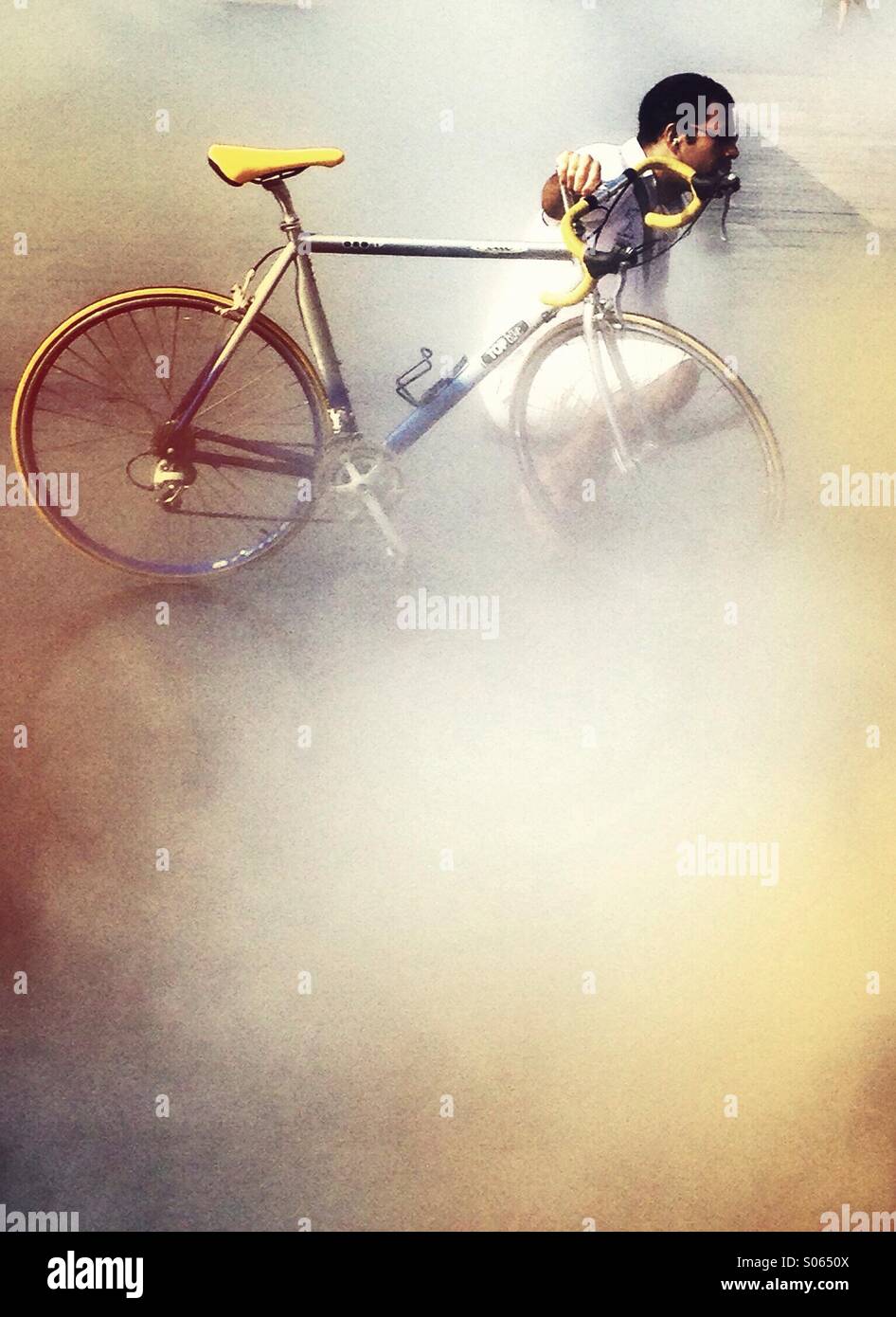 Man kneeling by his bicycle in a mist - Smartphone Captured Stock Image