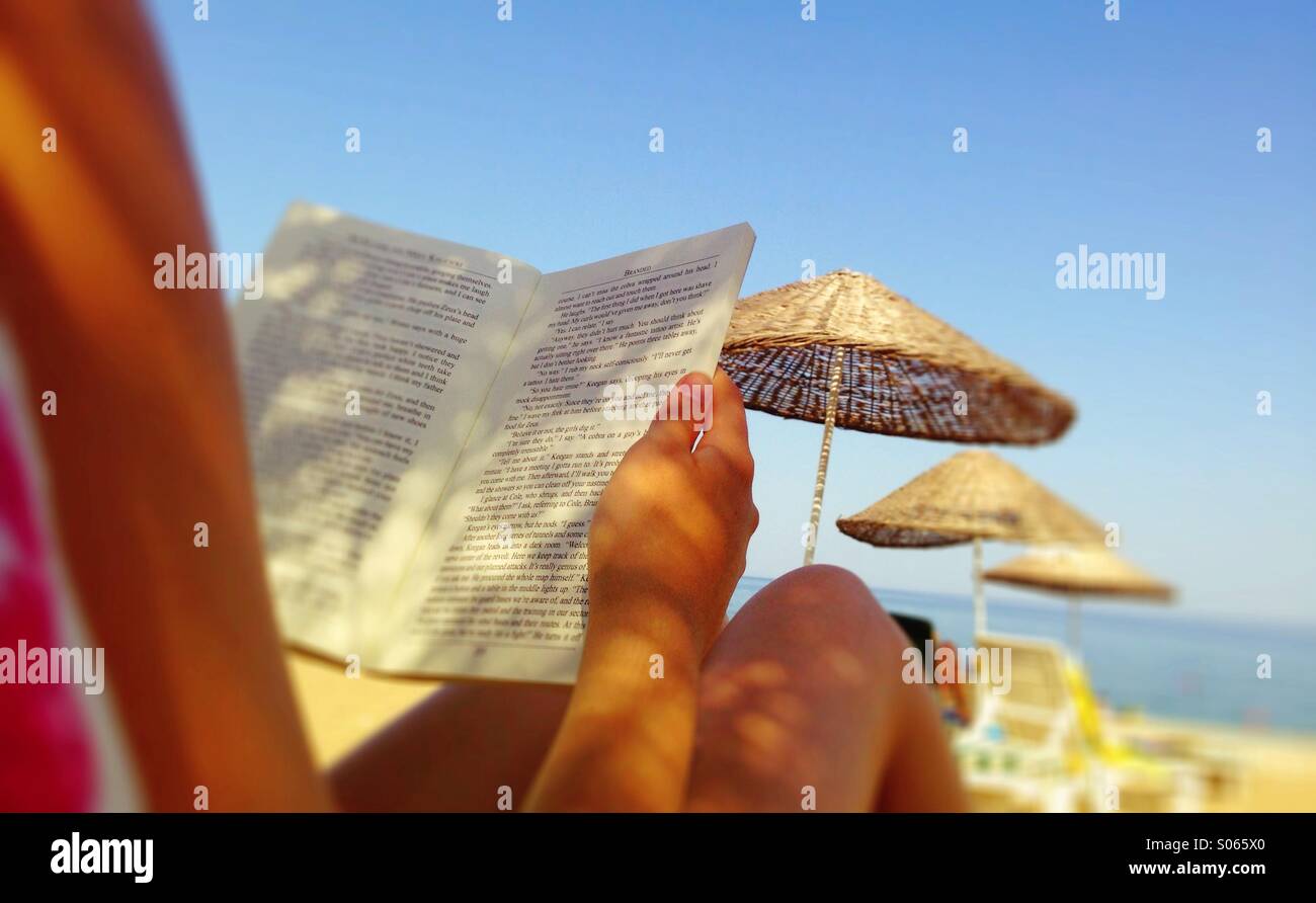 Summer holiday reading, relaxing on the beach. Stock Photo