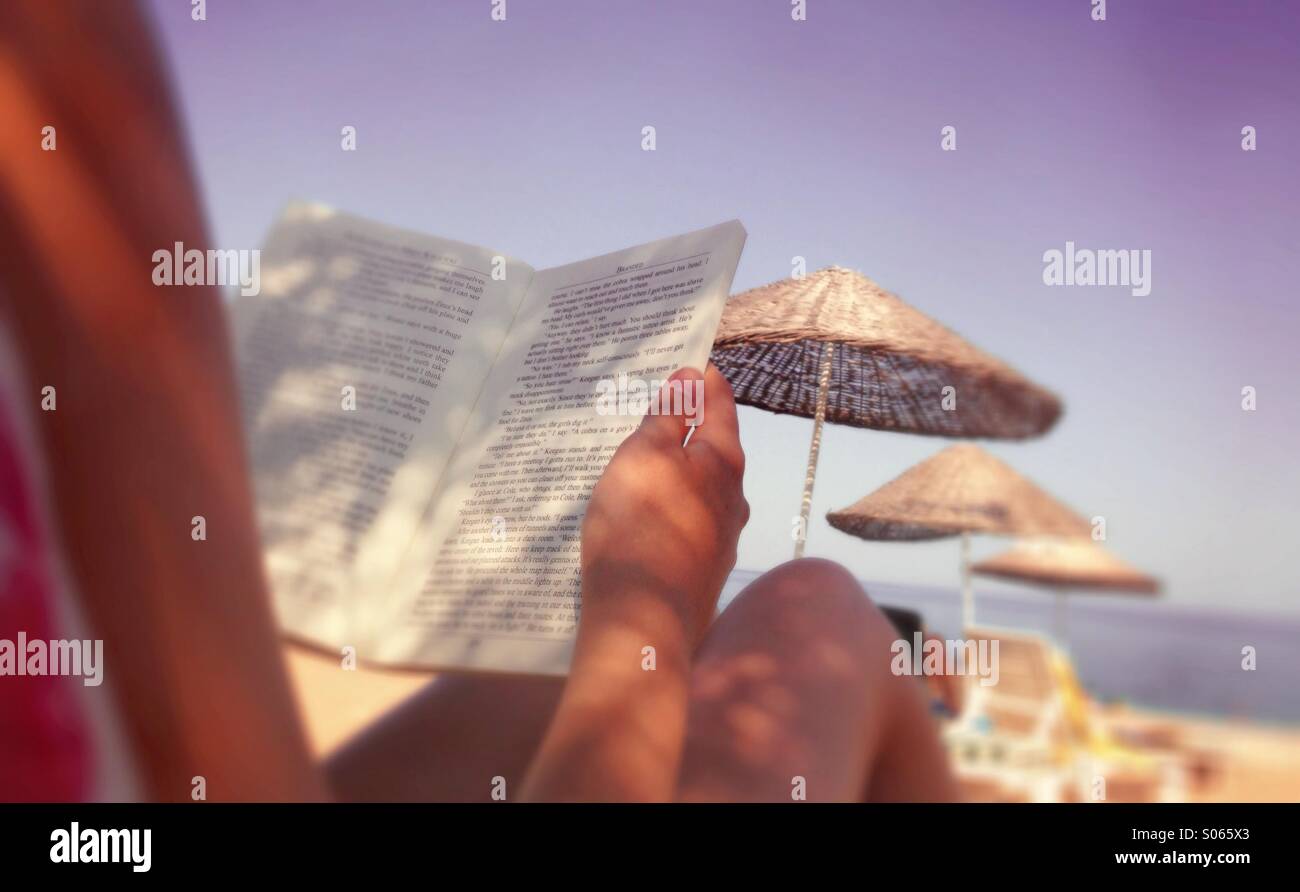 Summer holiday - teenager reading on the beach. Stock Photo