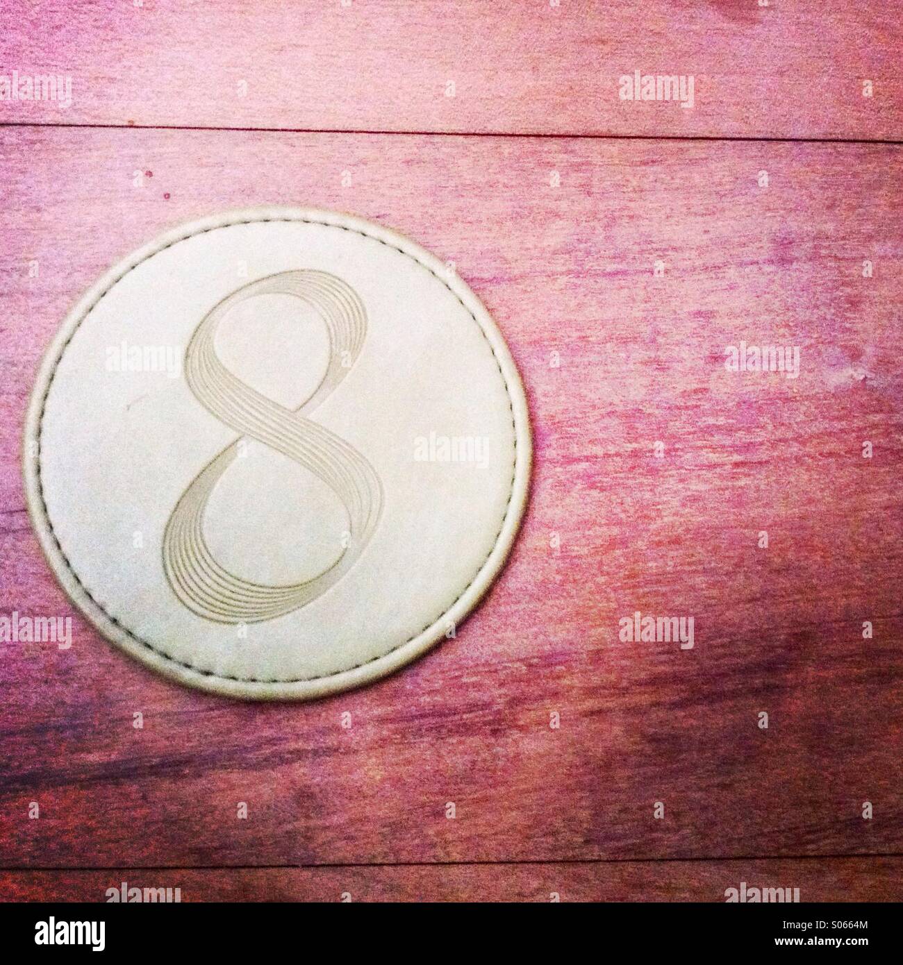A coaster with the number eight sitting on a table. - Smartphone Captured Stock Image