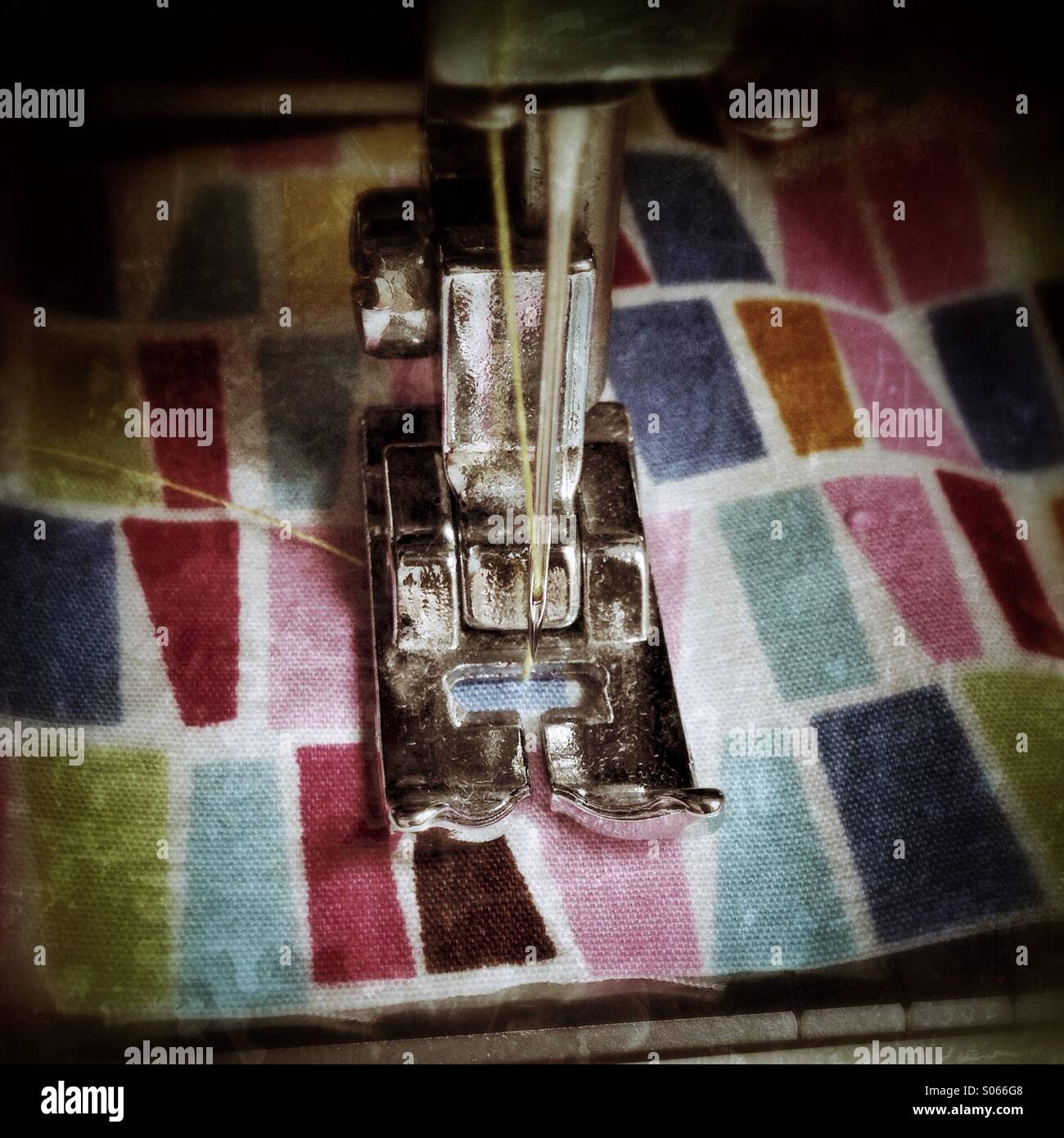 Sewing machine sewing multi coloured fabric, with grunge effect Stock Photo