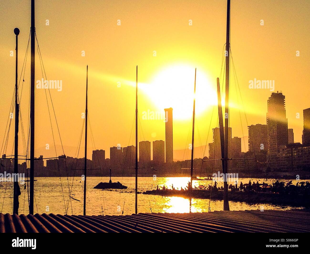 View of Benidorm skyline at sunset through yacht masts Stock Photo