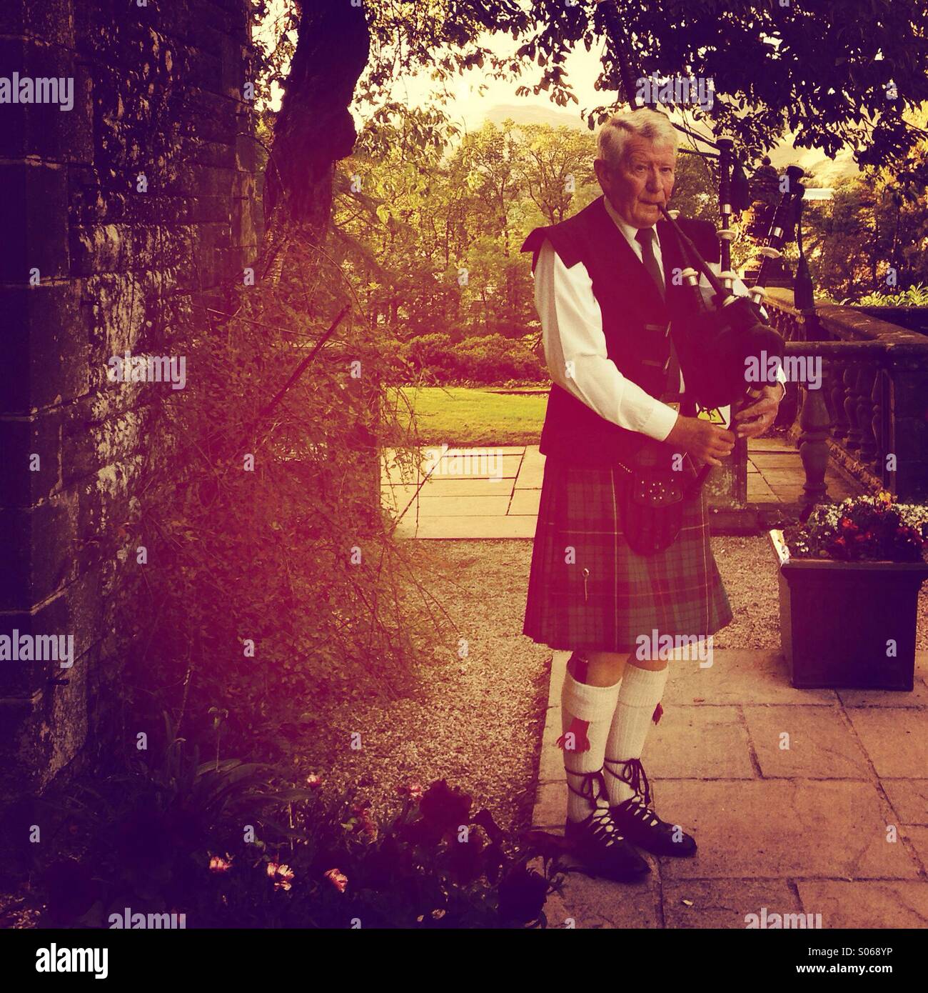 Piper playing bagpipes in Scottish wedding venue Stock Photo
