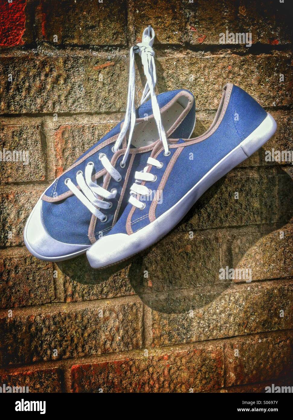 Canvas shoes hanging on a wall from a nail - Smartphone Captured Stock Image