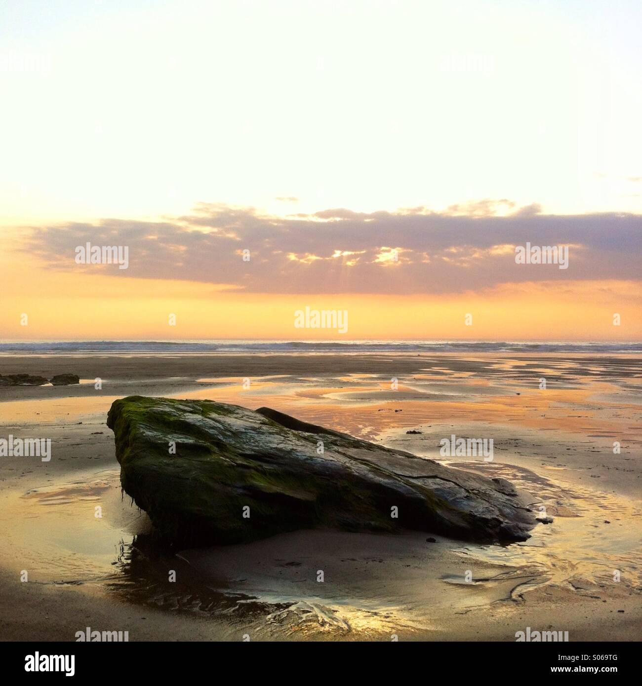 A rock at the beach at sunset. Watergate bay, newquay Cornwall England UK. - Smartphone Captured Stock Image