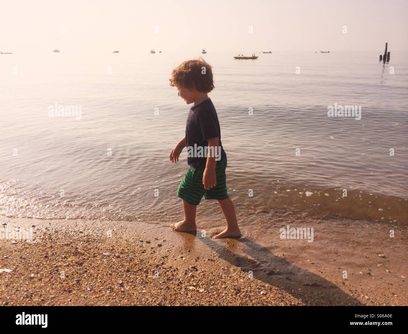 A little boy playing on a sunny beach during summer in Connecticut, USA. Stock Photo