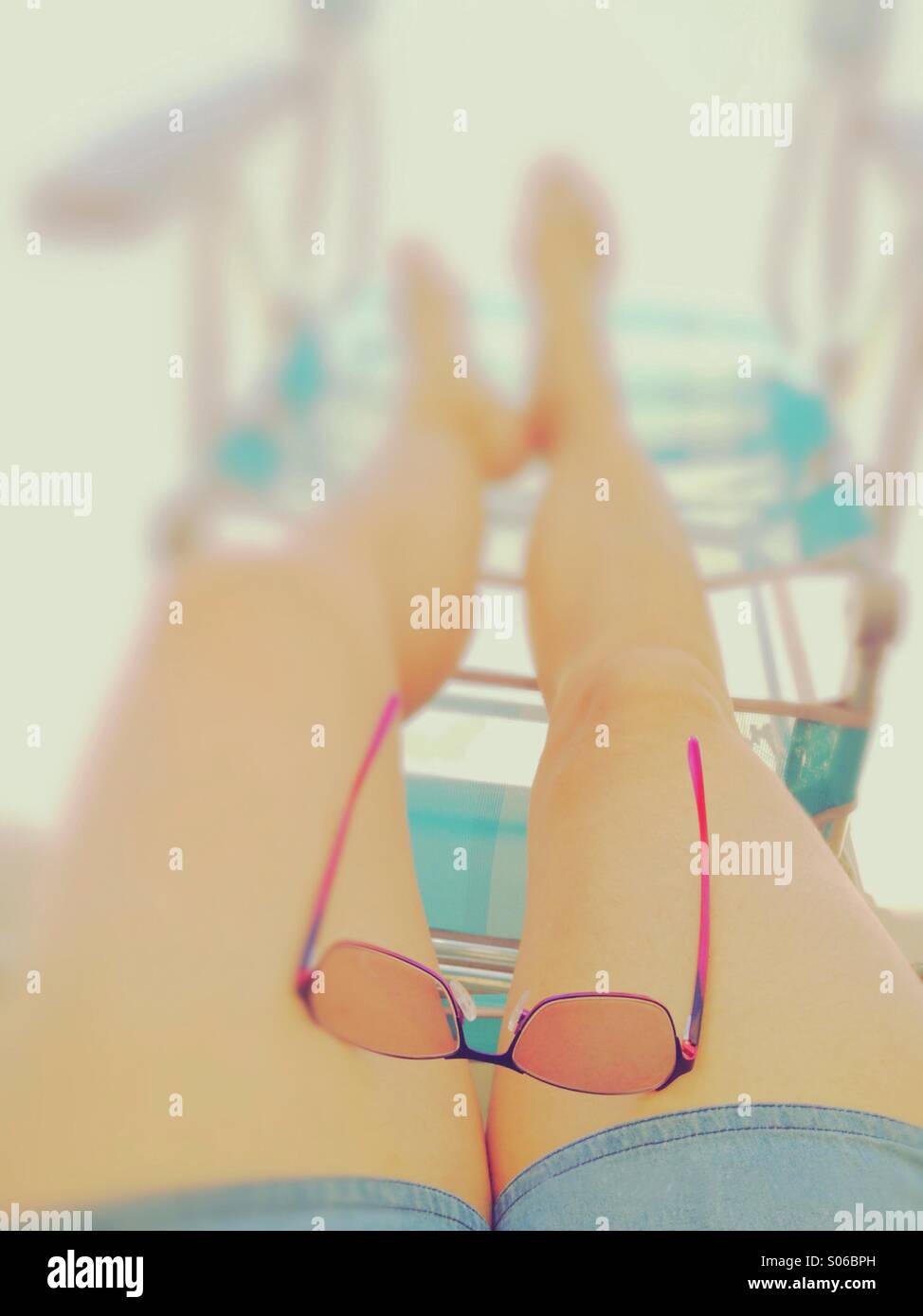 Lazy Days - Lady's legs relaxing in on a deck chair with sun glasses on her lap. - Smartphone Captured Stock Image