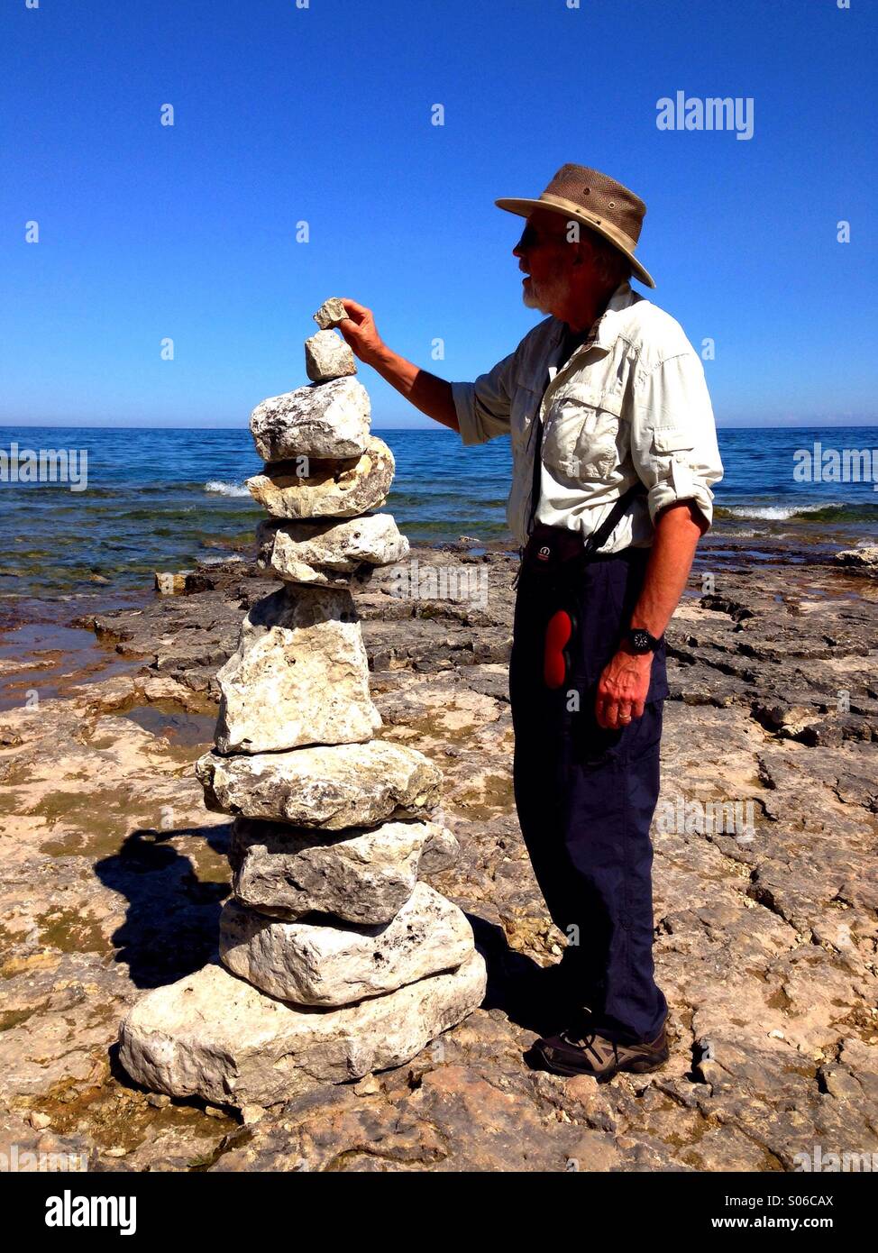 Finishing touches on lake shore rock art - Smartphone Captured Stock Image