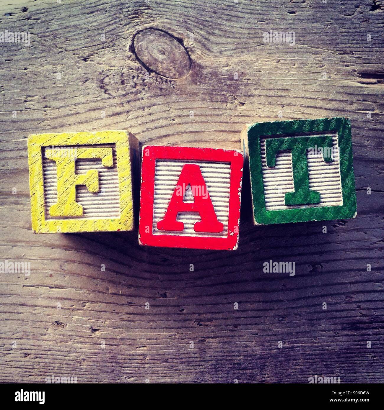 It's a photo of woodblocks toy with alphabet letters on them that are combined together to form the word FAT Stock Photo