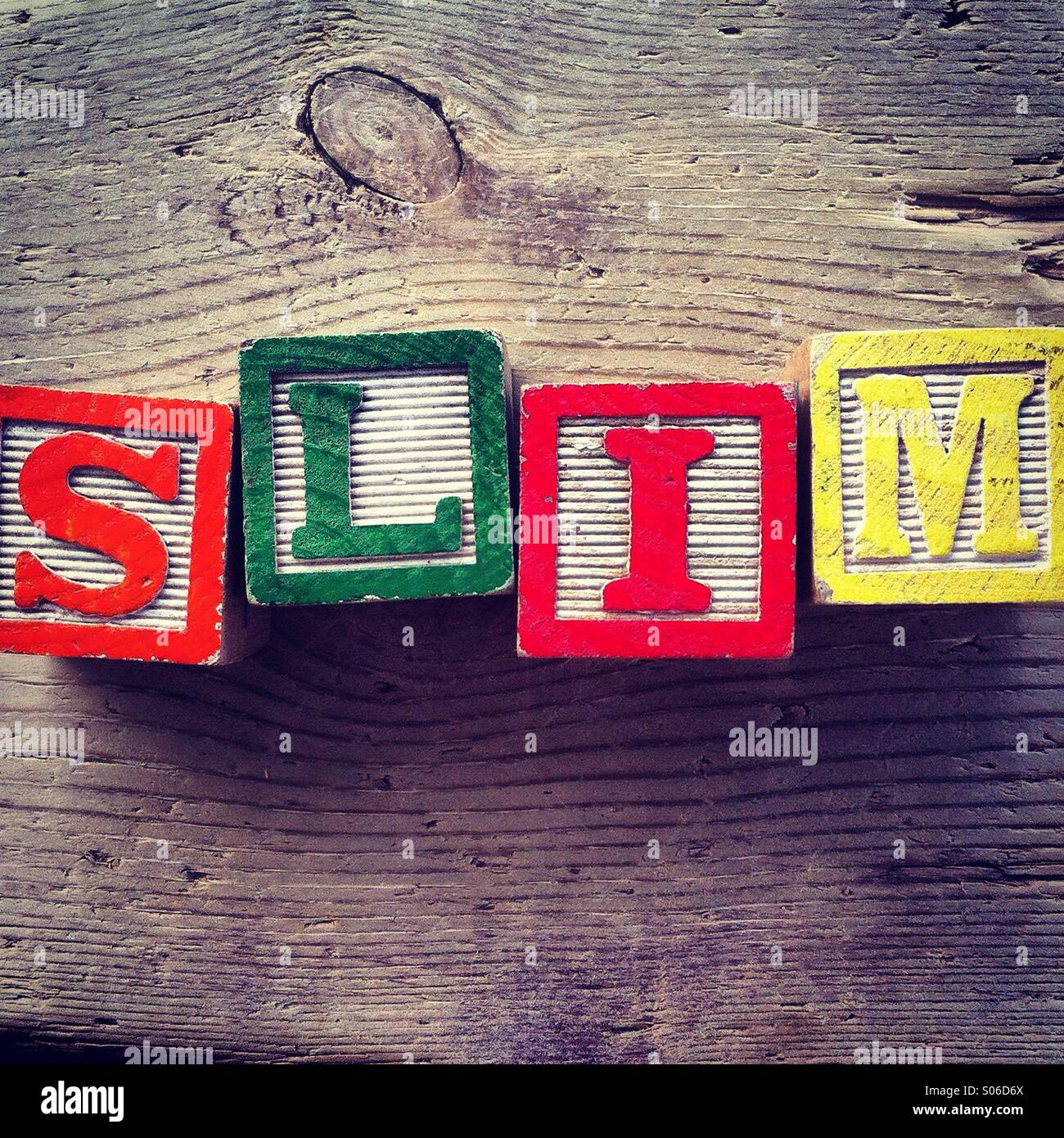 It's a photo of woodblocks toy with alphabet letters on them that are combined together to form the word SLIM - Smartphone Captured Stock Image