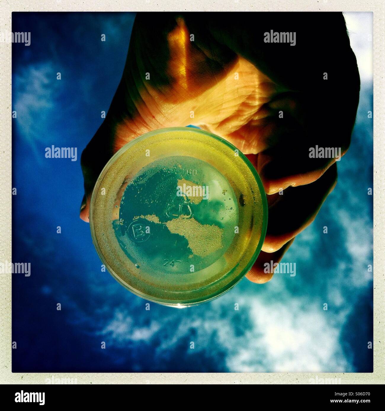 A looking up shot a hand holding a glass with liquid in it. Stock Photo