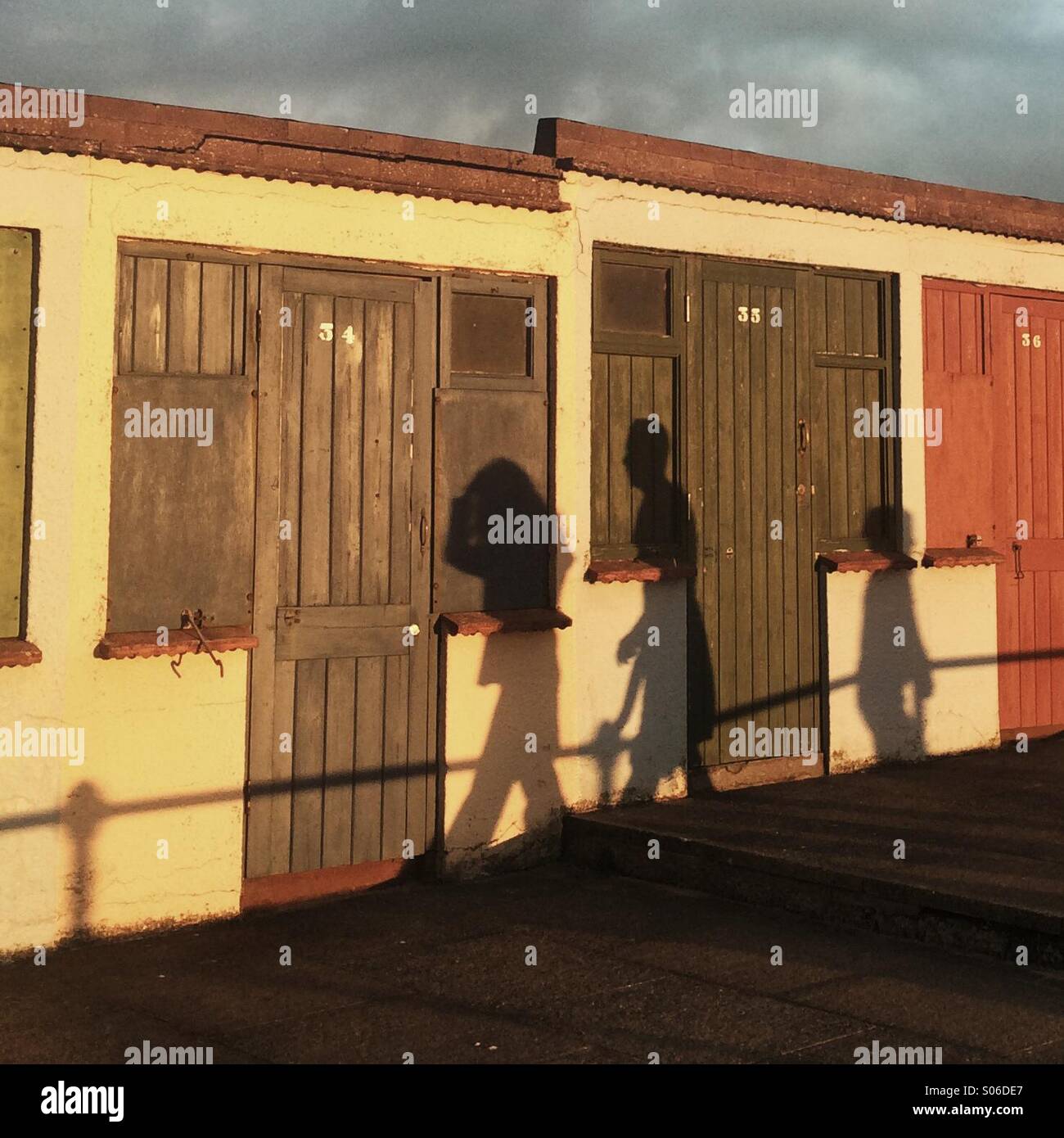 Shadows of people walking past beach huts - Smartphone Captured Stock Image