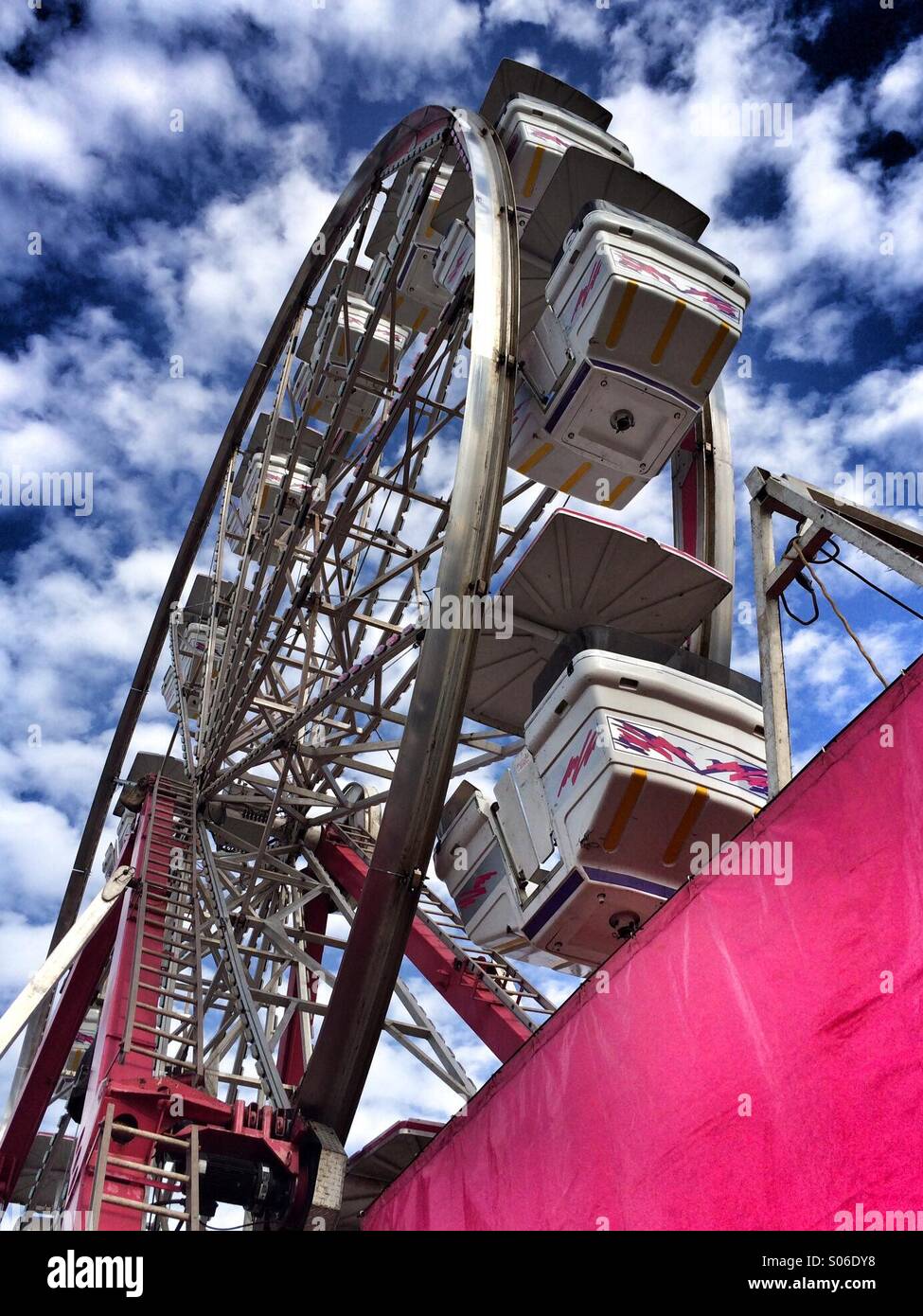 A large Ferris wheel against a blue cloudy sky at the fair Stock Photo