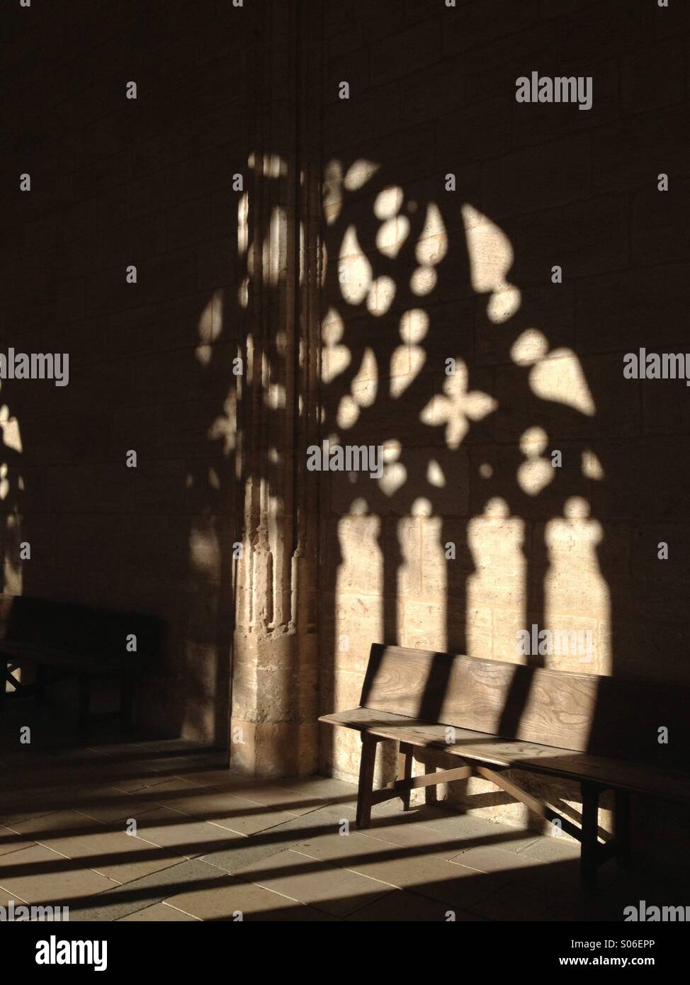 Wooden bench and shadow from a stone carved arch at Segovia Cathedral in Spain - Smartphone Captured Stock Image