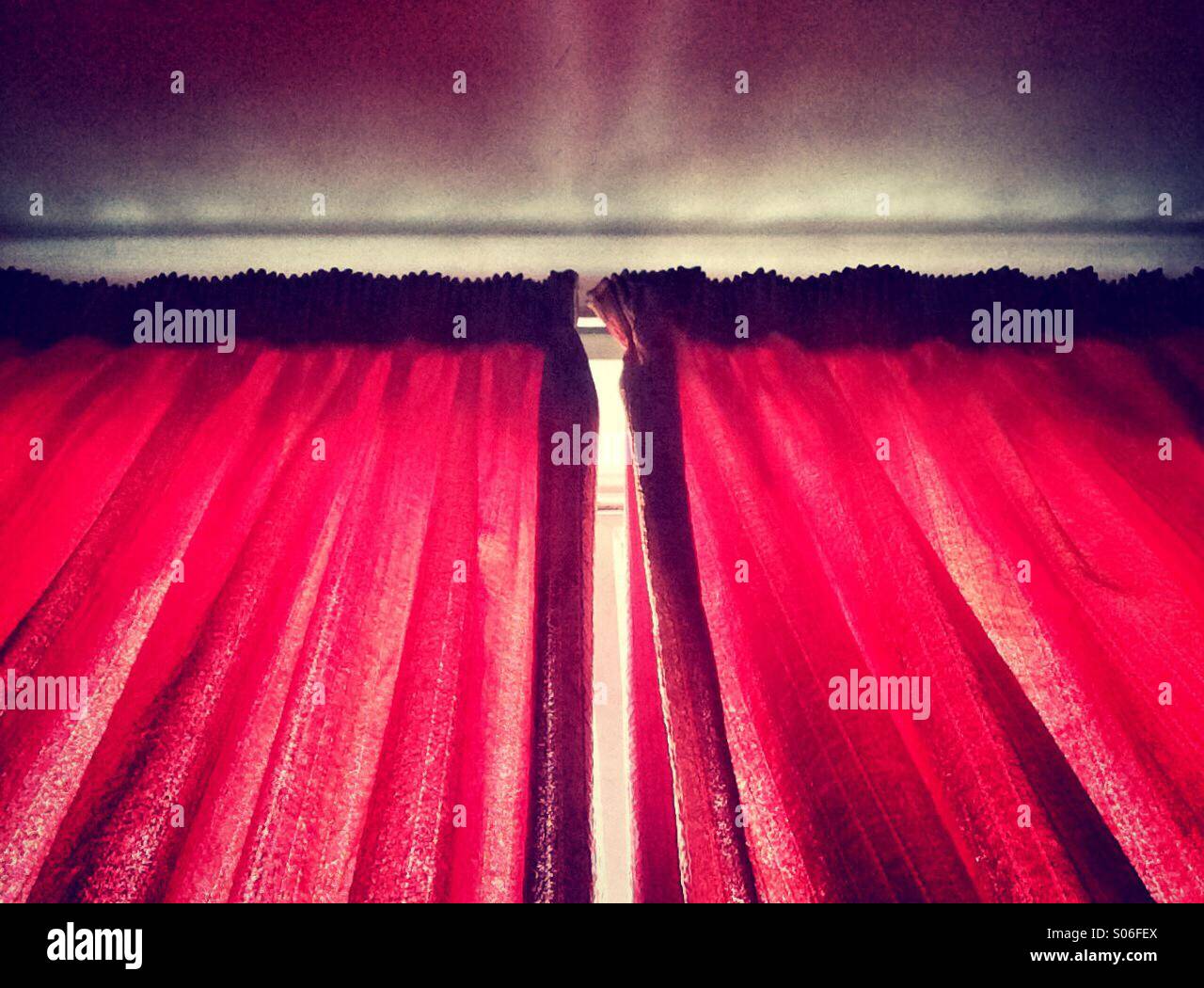 Sunlight streaming in though red curtains Stock Photo