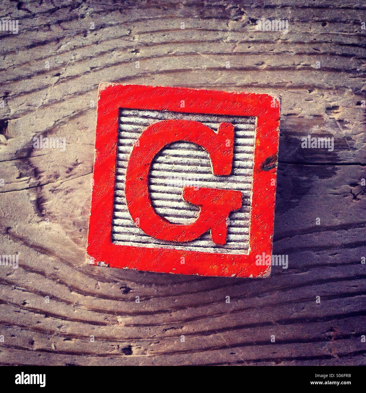 It's a woodblock toy with an alphabet letter on it: G - Smartphone Captured Stock Image