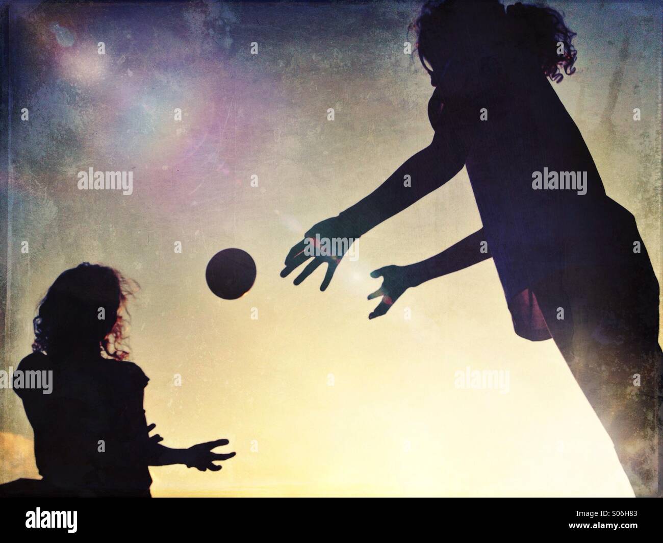 Two girls in silhouette throwing ball between them - Smartphone Captured Stock Image
